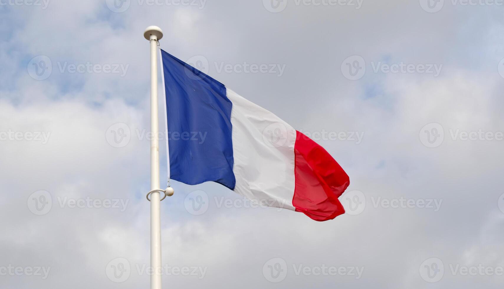 French national flag waving on cloudy sky background. The flag on a flagpole flutters in the wind. The image conveys the spirit of France. freedom, equality, fraternity. photo