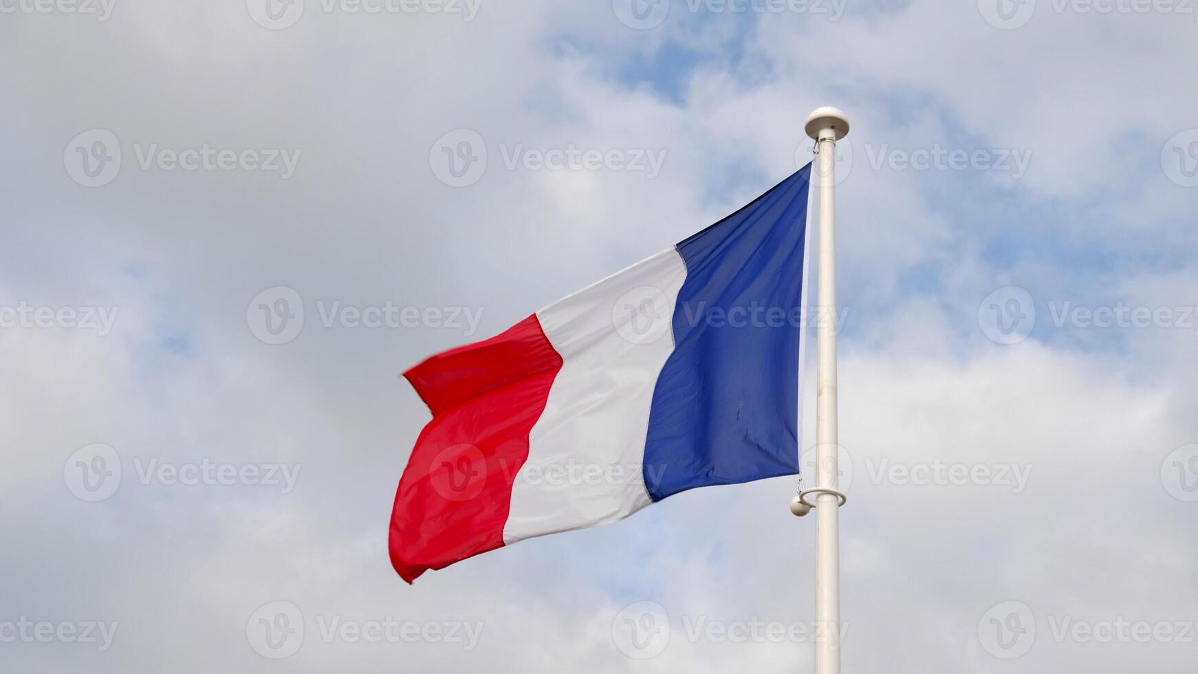 French national flag waving on cloudy sky background. The flag on a flagpole flutters in the wind. The image conveys the spirit of France. freedom, equality, fraternity. photo