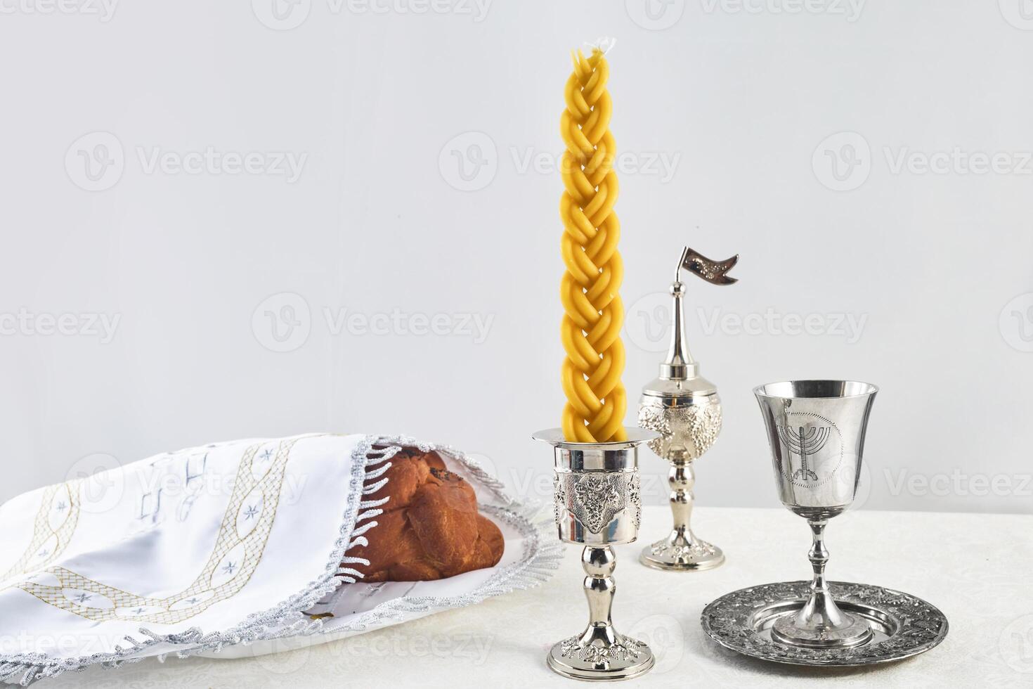 Shabbat Table Setting. Challah bread, braided candle and silver Kiddush cup, photo