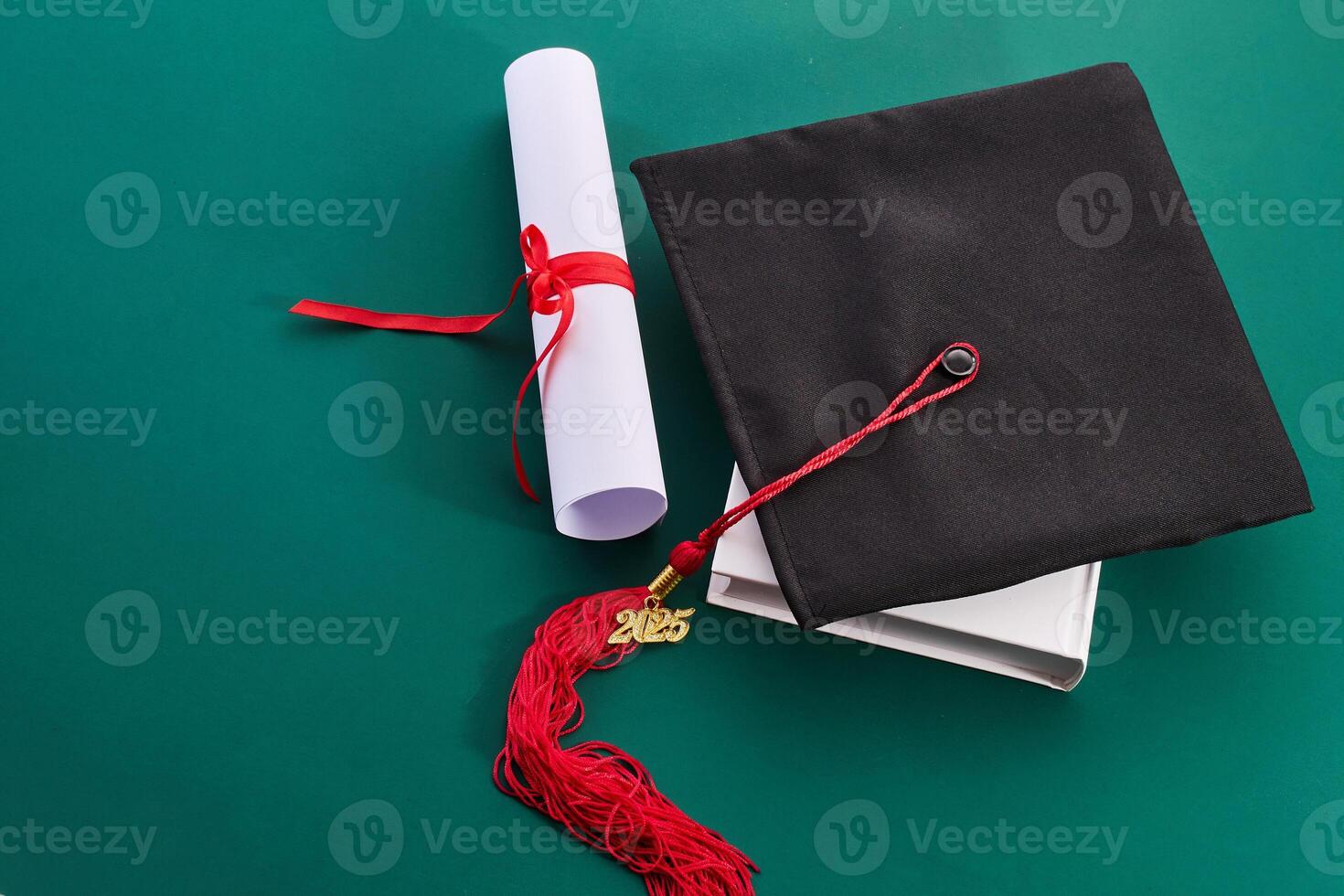 Graduation Essentials. Cap and diploma on green background photo