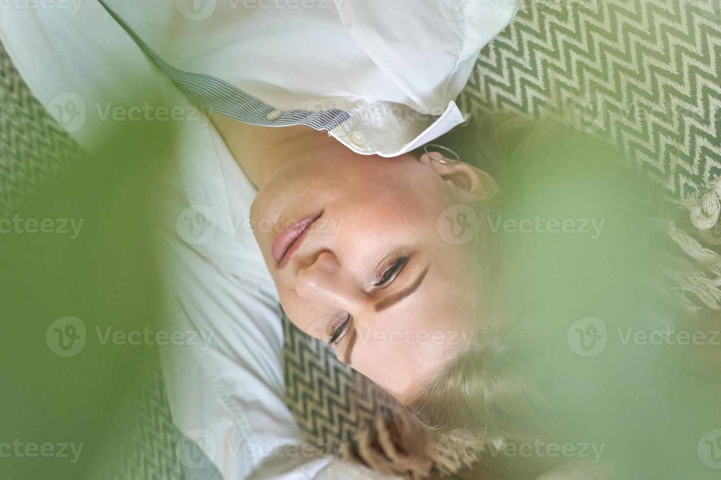 Relaxed caucasian female lying on zigzag pattern rug with green leaves for a natural soothing atmosphere. photo