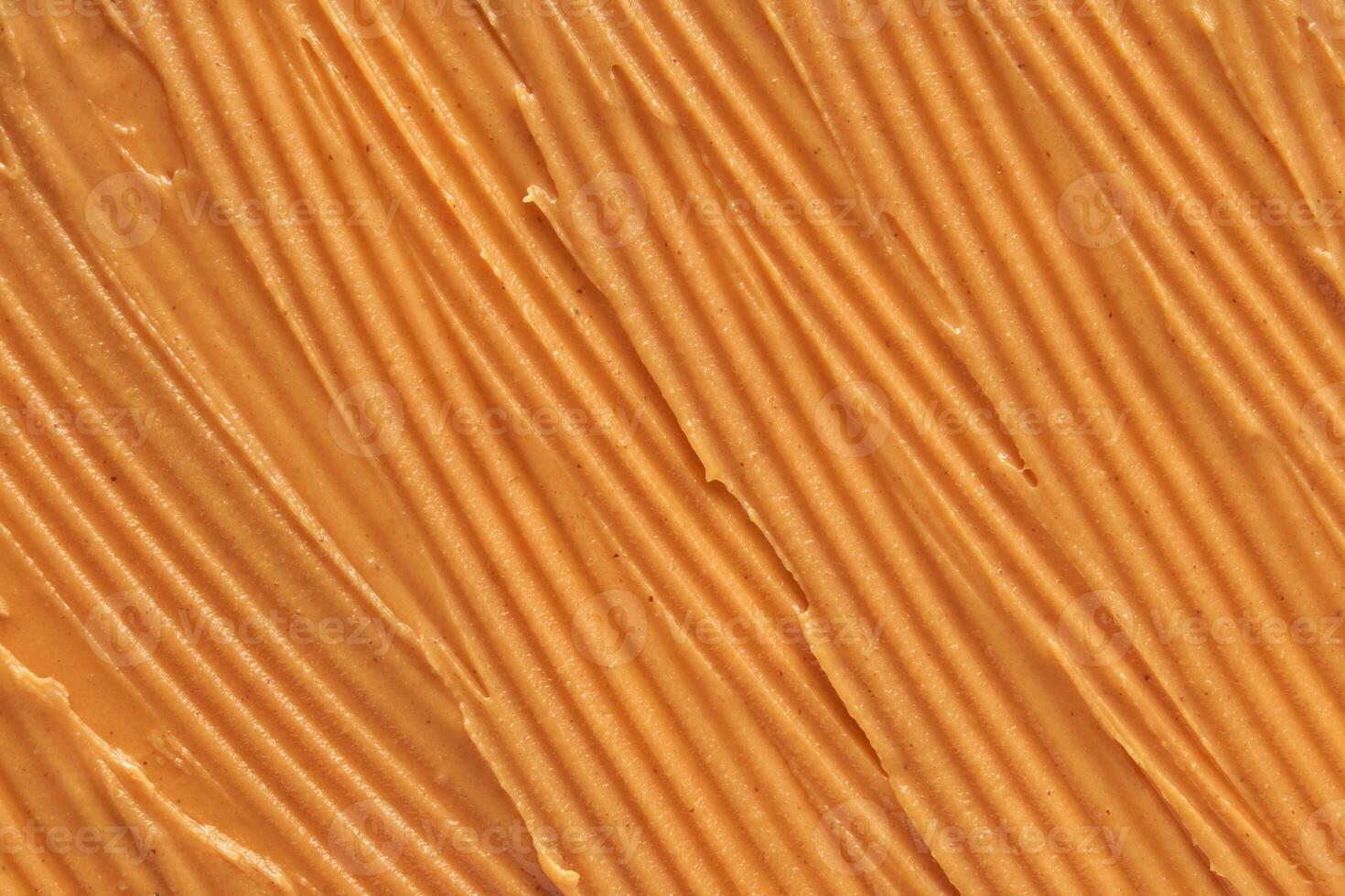 Smooth peanut butter texture with evenly spread creamy surface highlighting rich golden brown hue. photo