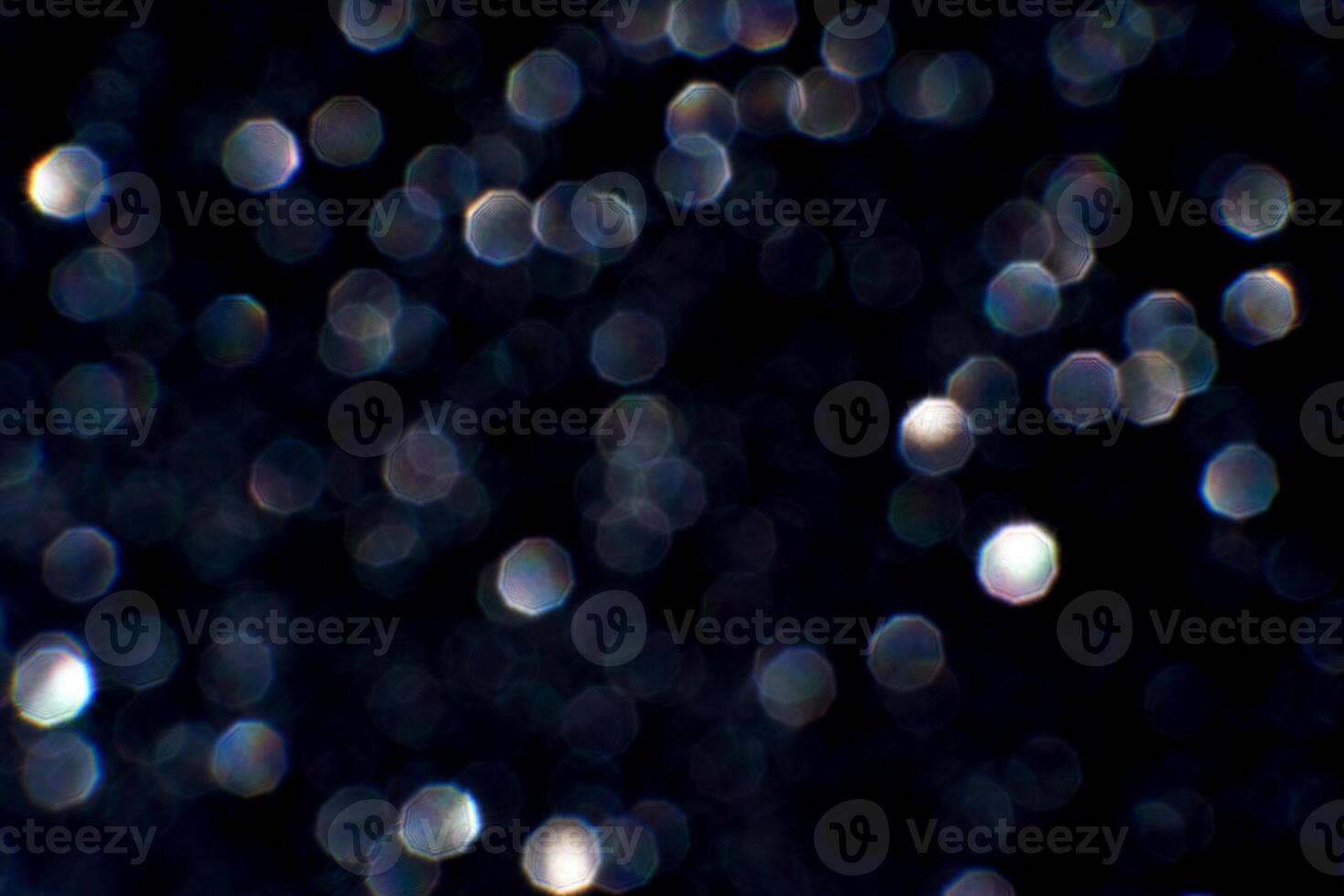 Sparkling bokeh lights on a dark background with hexagonal shapes and soft glow effects. photo