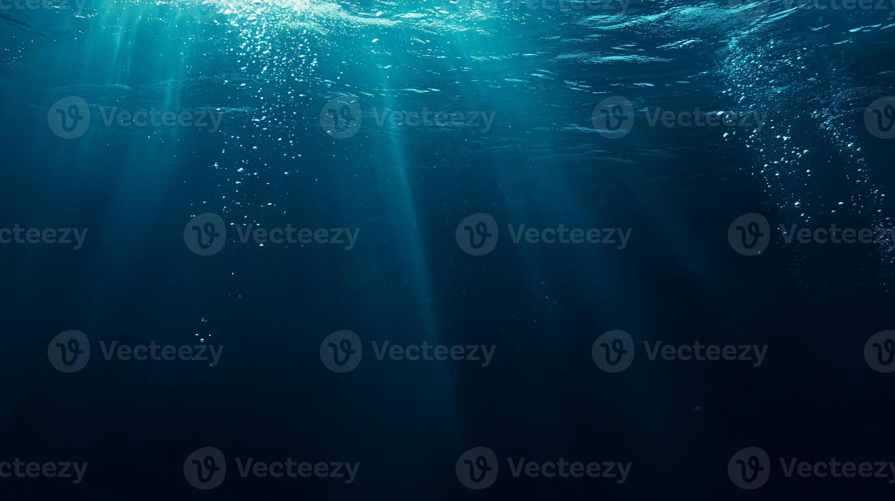 Sunbeams illuminate deep ocean water, bubbles rise from below. photo