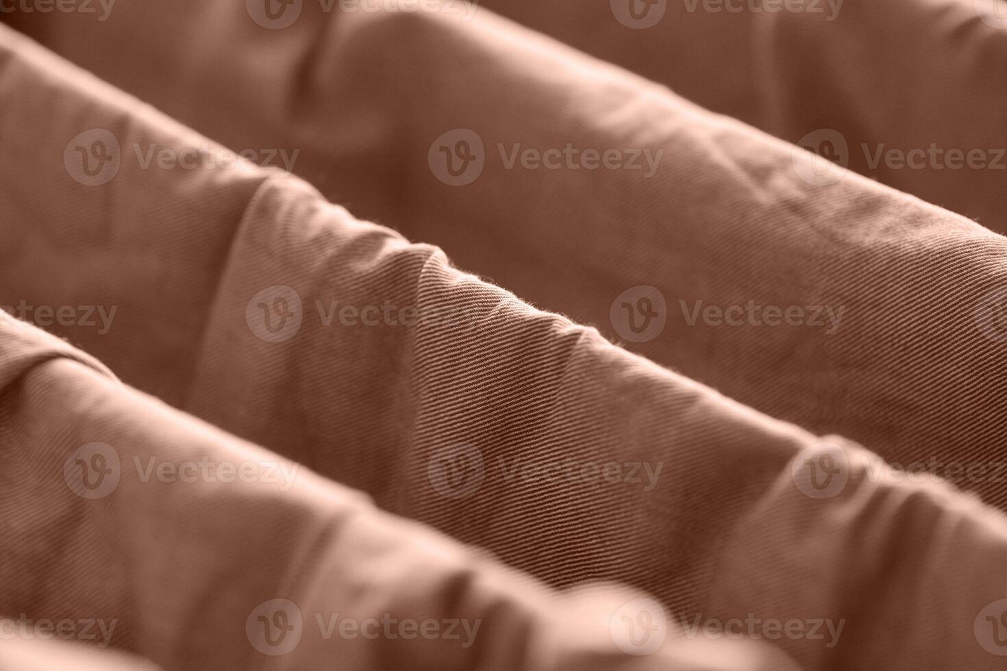 Close up of brown fabric folds with soft texture and diagonal patterns in a warm tone. photo