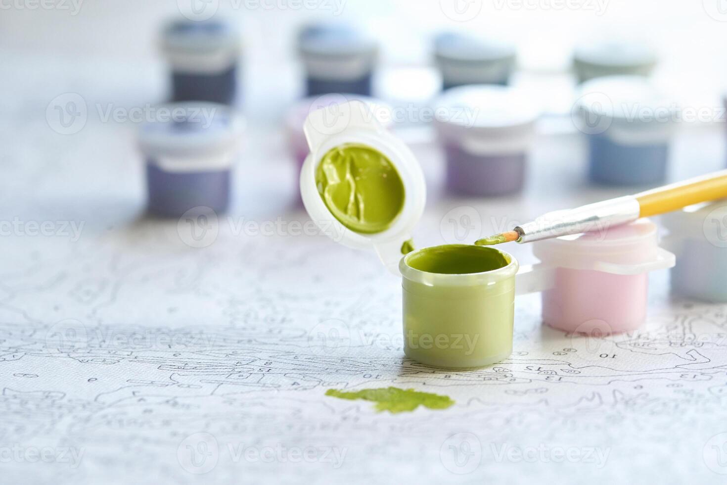 Creative art setup with paint by numbers kit. brush, green paint pot, and colorful palette on artistic canvas. photo