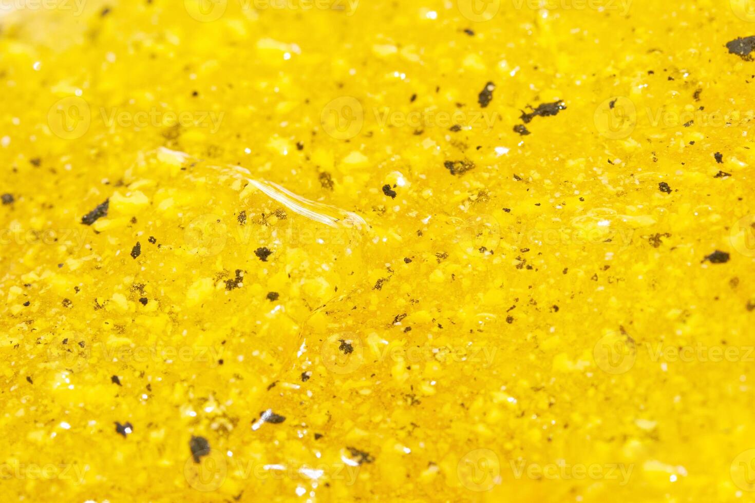 Close up of vibrant yellow slime with textured grains and shimmering surface. photo