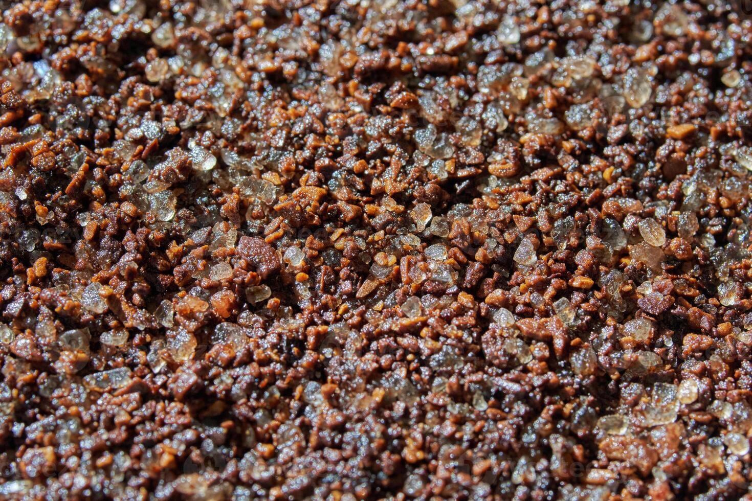 Close up of coarse brown sugar and coffee granules blended together in a textured surface view. photo