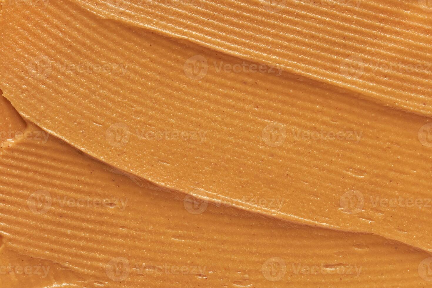 Close up of smooth peanut butter texture with natural brown color and creamy swirls. photo