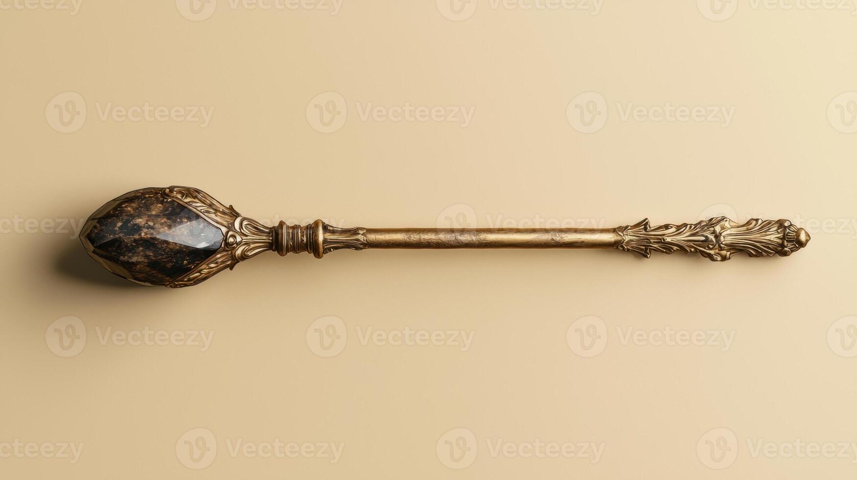 Ornate golden scepter with dark gemstone top on beige background photo