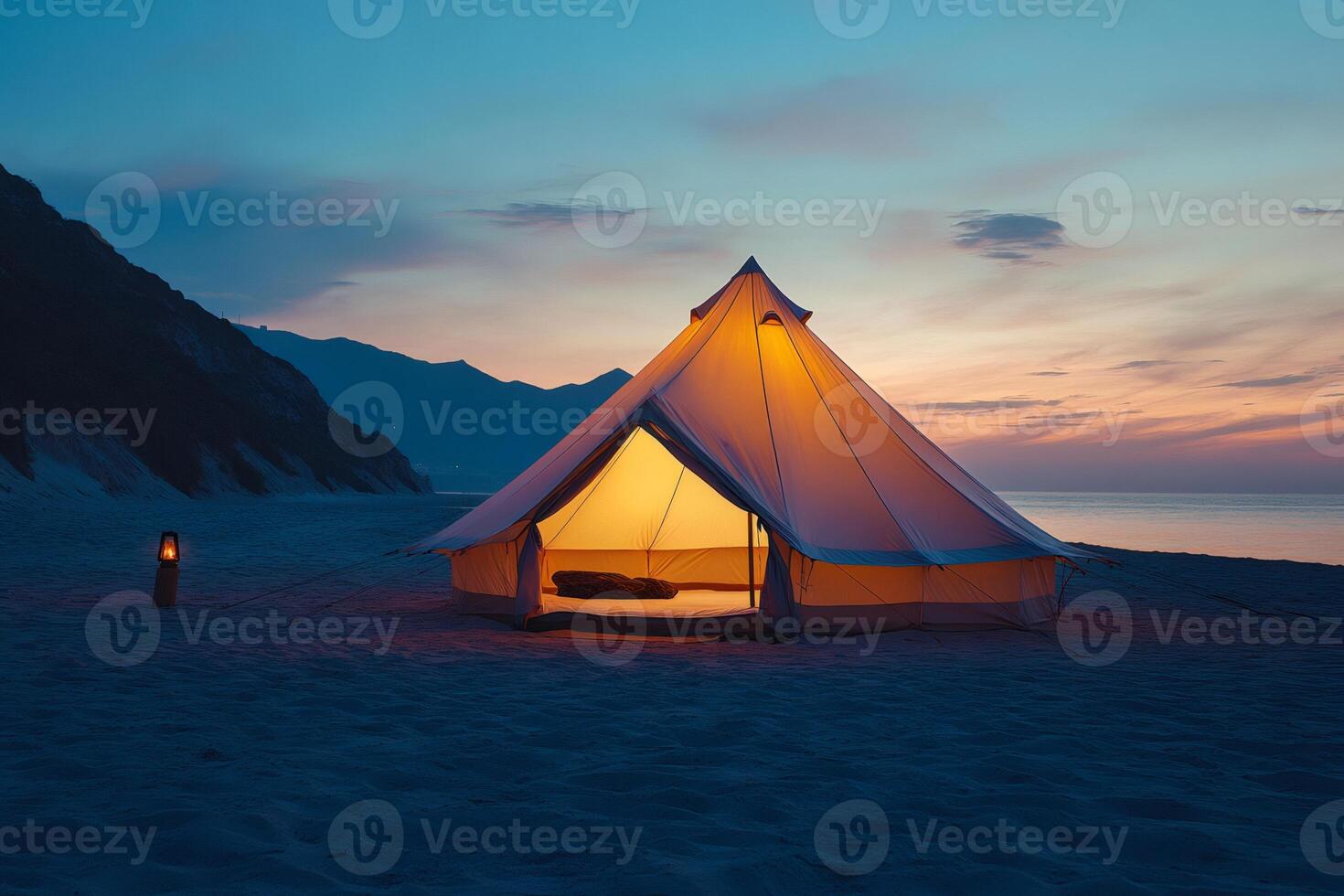 Illuminated tent invites campers to relax on sandy beach at sunset photo