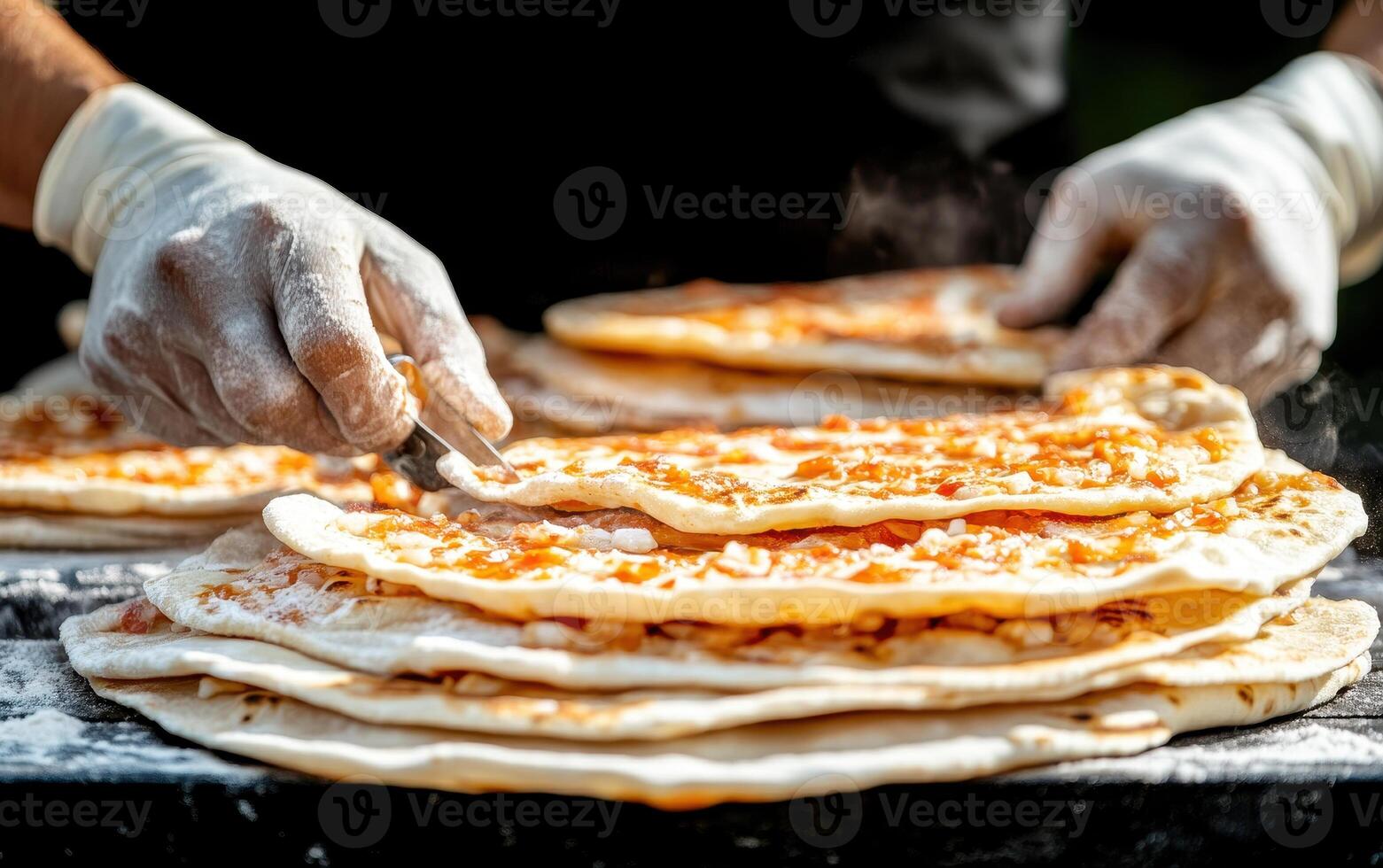 Freshly prepared flatbreads are being topped with ingredients by chef wearing gloves. scene captures art of street food preparation, showcasing delicious culinary skills photo