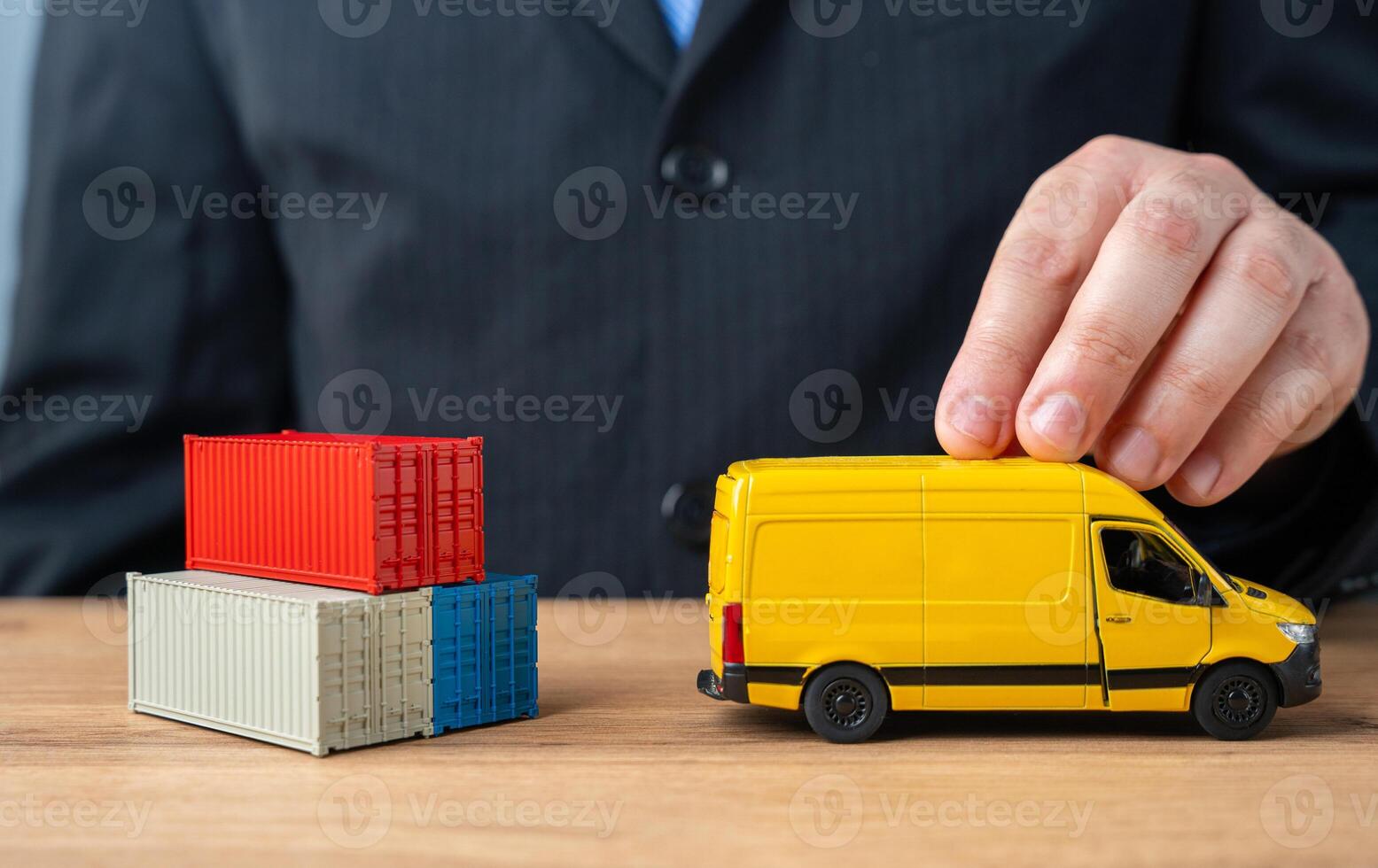 A businessman pushes a delivery van past a stack of shipping containers. The concept of delivery and transportation of goods and parcels to the end customer. Logistics and speed. photo