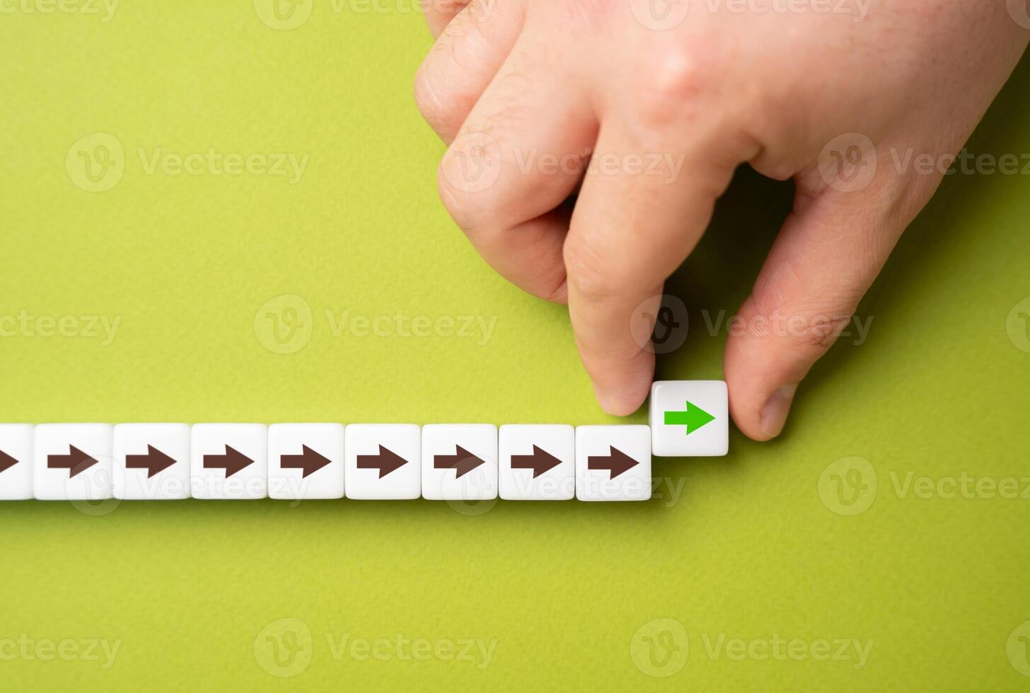 A hand makes a path out of blocks with arrows. The concept of moving forward and continuing progress. Strategic planning, forward momentum, and the continual pursuit of growth and improvement photo