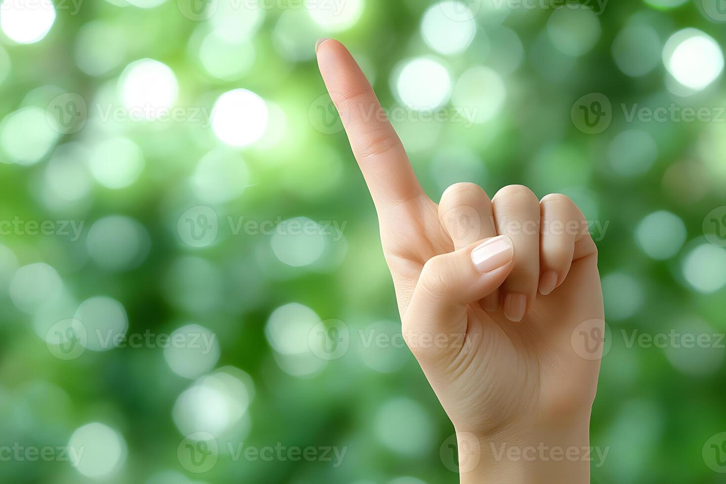 Gesturing Hand with Raised Index Finger Against Blurred Green Background for Communication Concepts photo