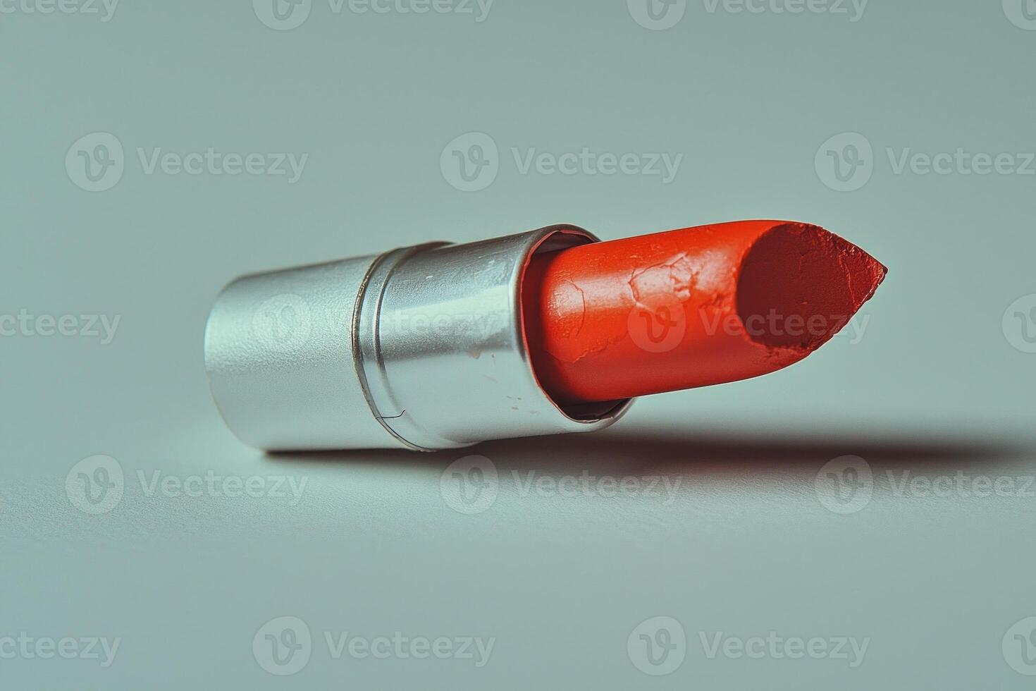 broken lipstick bullet rests on its side showcasing its bold red hue and creamy texture. pristine white background highlights rich pigment and details of broken surface photo