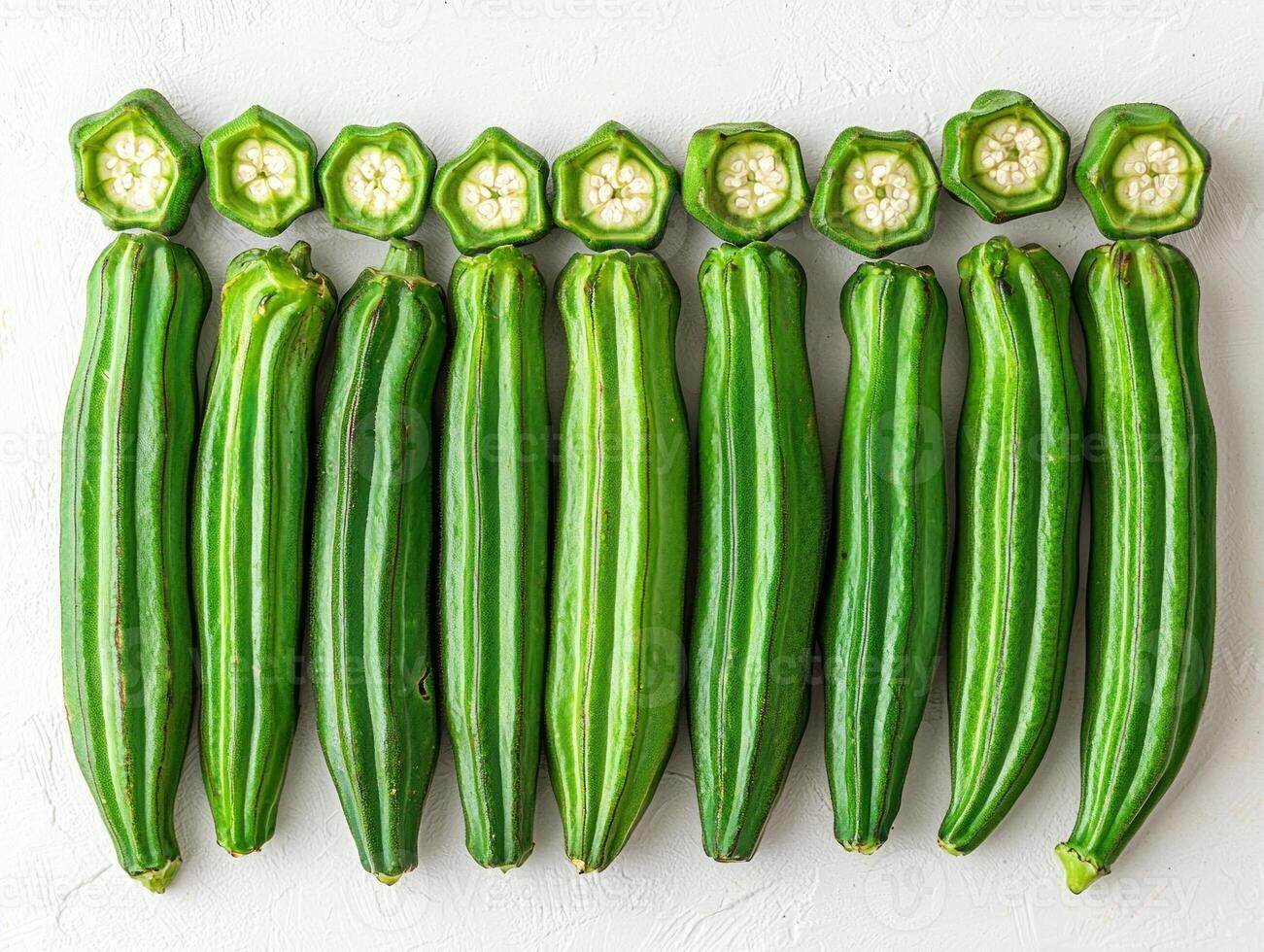 Fresh okra pods are neatly arranged in fan shape highlighting their smooth green surfaces and unique texture. background is plain white enhancing freshness of pods photo