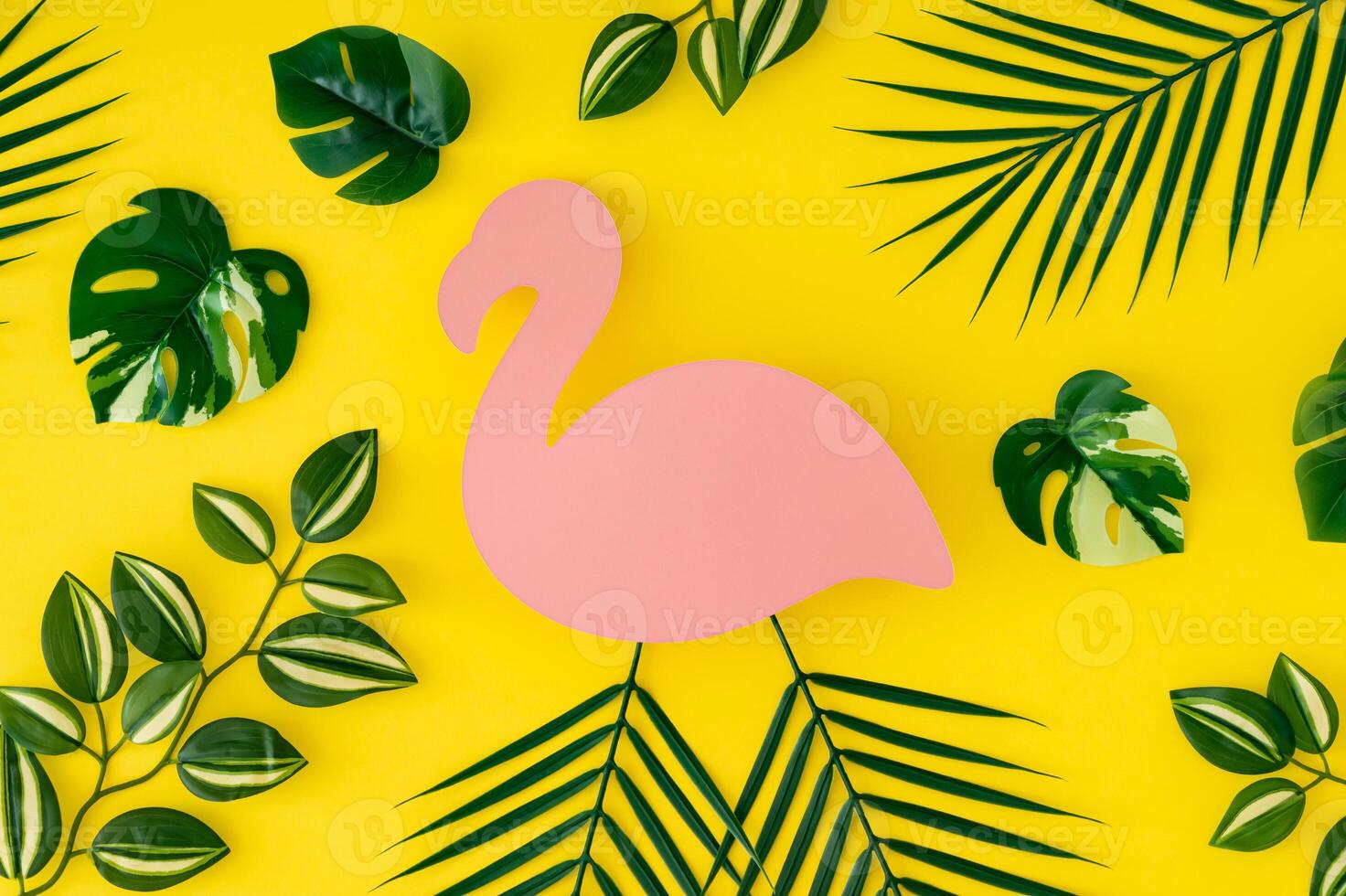 Trendy summer pattern composition made of tropical green leaves on yellow background with pink flamingo paper card note copy space. Minimal creative summer concept. Nature backdrop idea. Flat lay. photo