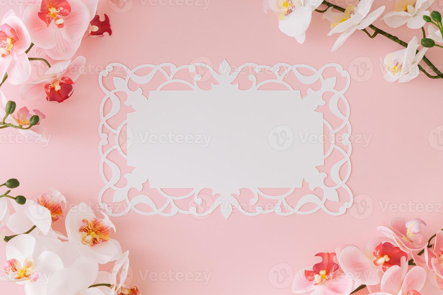 Beautiful orchid flower on light pastel pink background with white paper card note copy space. Minimal spring and summer concept. Flowers aesthetic. Flat lay, top of view. photo