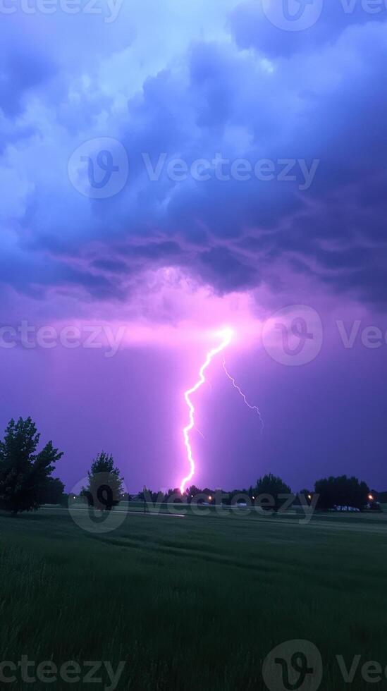 Dramatic Lightning Strike Against Dark Cloudy Sky Capturing Intense Stormy Atmosphere with Vibrant Purple and Blue Hues in Scenic Landscape Setting During Evening Thunderstorm photo