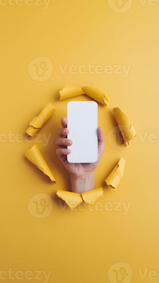 A vibrant yellow background with a hand breaking through, holding a blank object Vertical Mobile Wallpaper photo