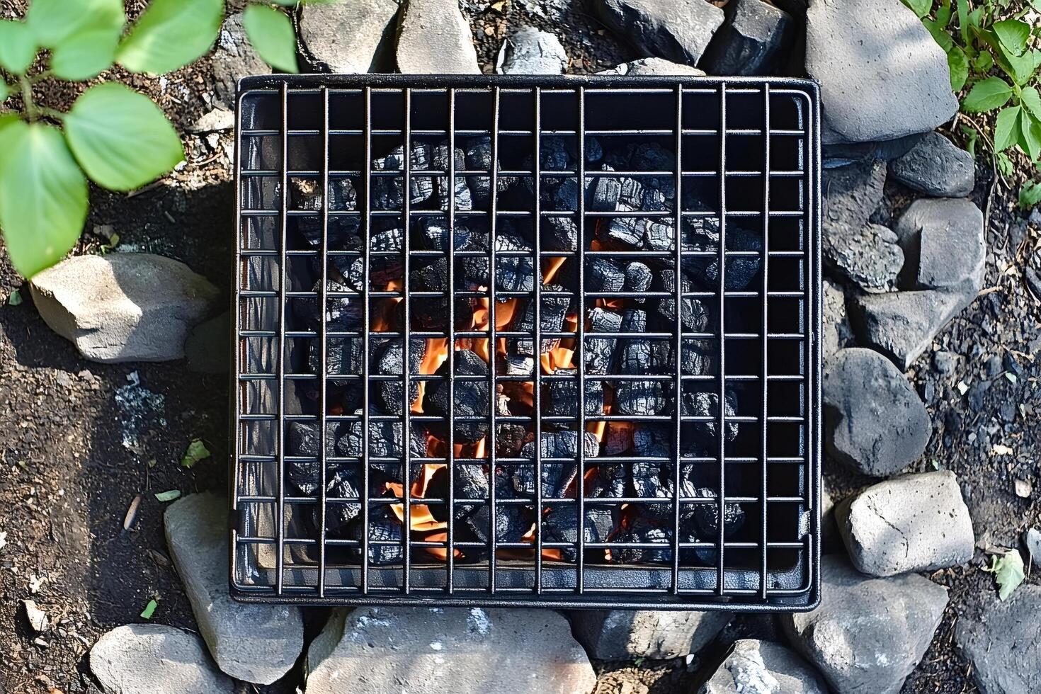 Burning charcoal briquettes glowing inside portable grill preparing for bbq photo