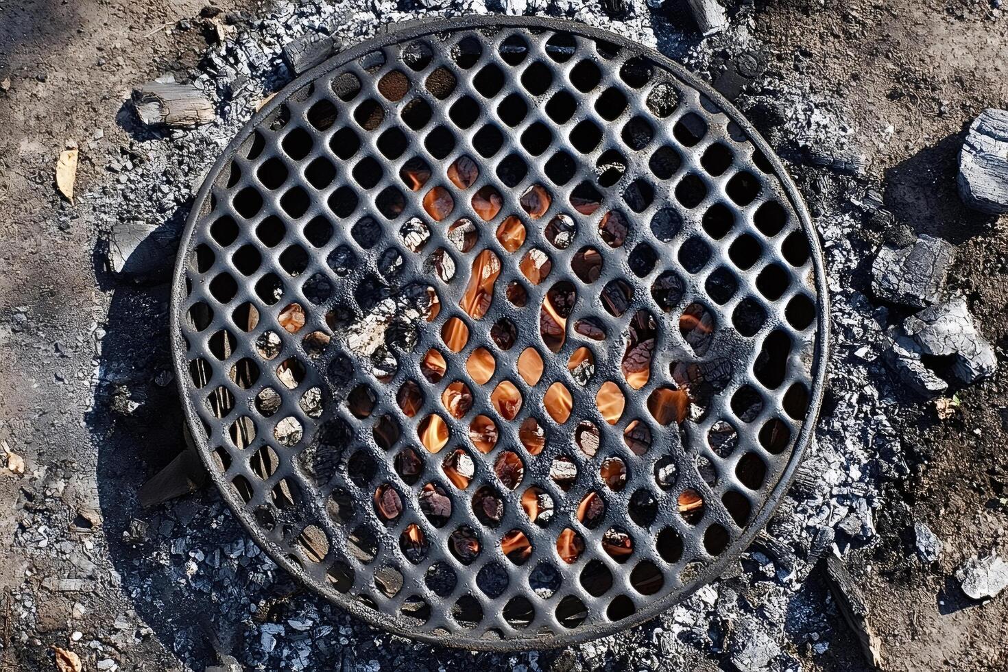 Burning charcoal under round metal grill generating heat for cooking photo