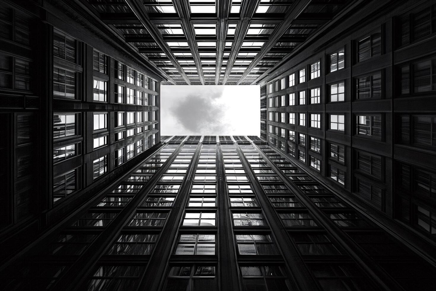 Looking up at the sky from the bottom of a skyscraper courtyard, black and white photo