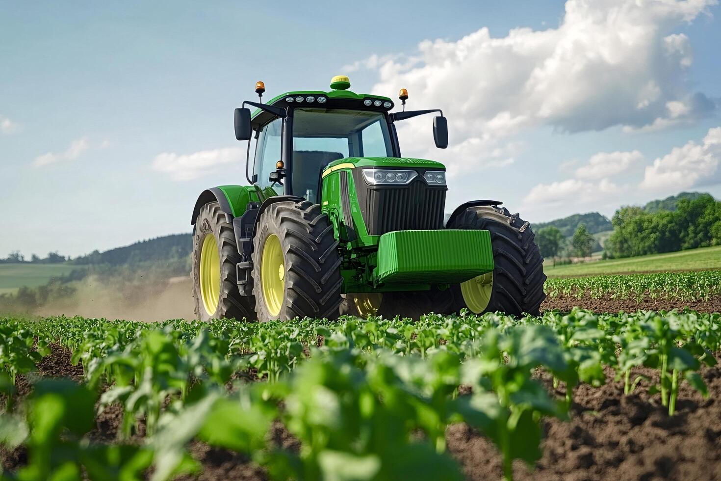 Powerful green tractor working on a field of young plants photo