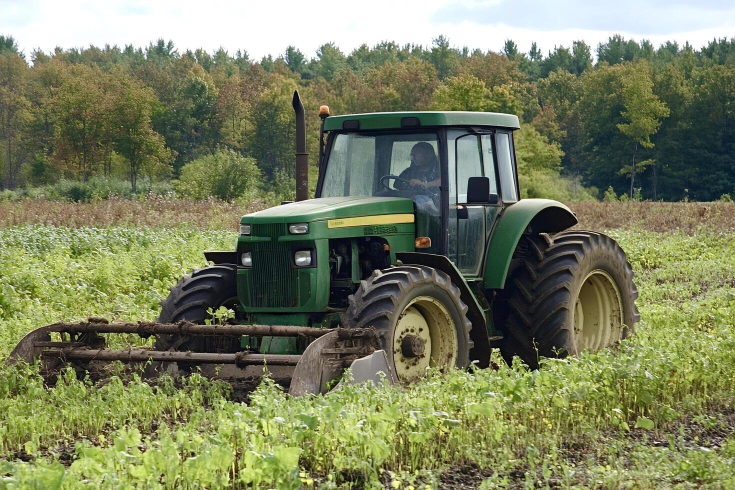 Farmer driving tractor and pulling hay rake in field photo