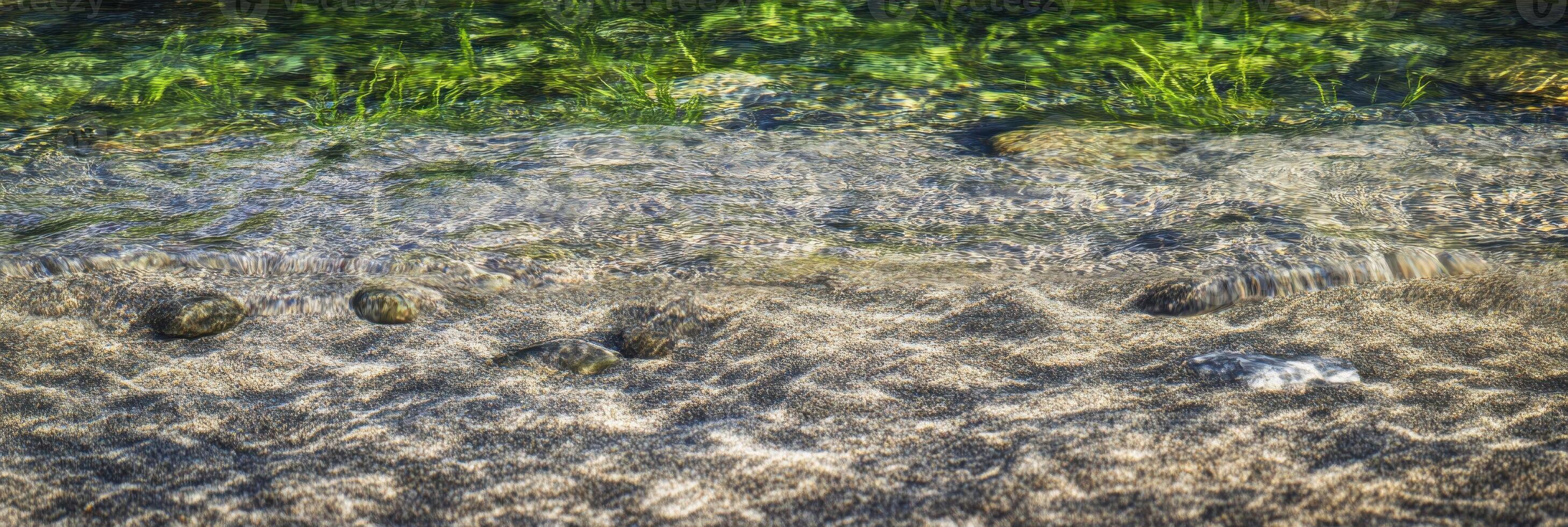 Clear streams gently flow over rocky riverbed with lush greenery photo