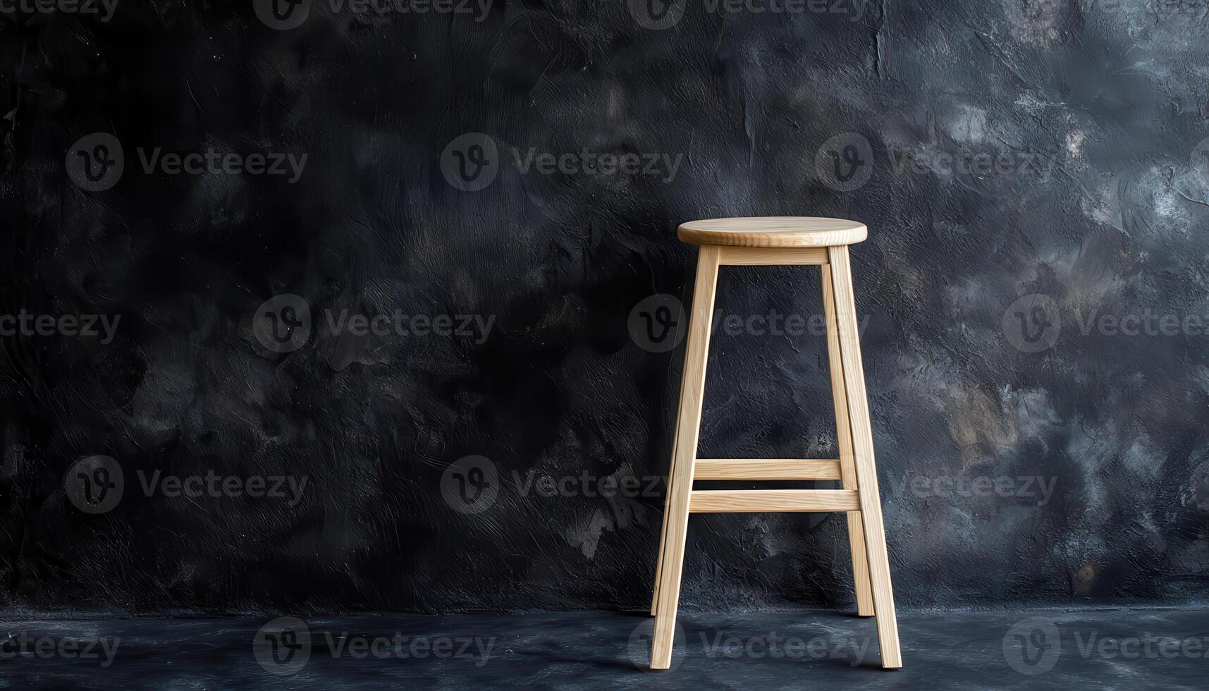 Simple Wooden Stool Against Dark Textured Wall photo