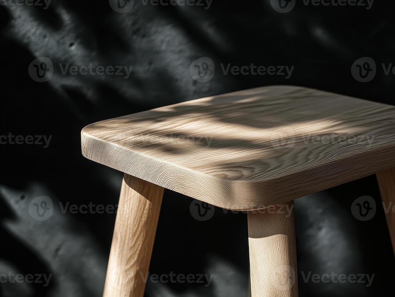 A Minimalist Wooden Stool Bathed in Sunlight Against a Dark Background, showcasing its natural grain and texture, a piece of simple elegant furniture photo
