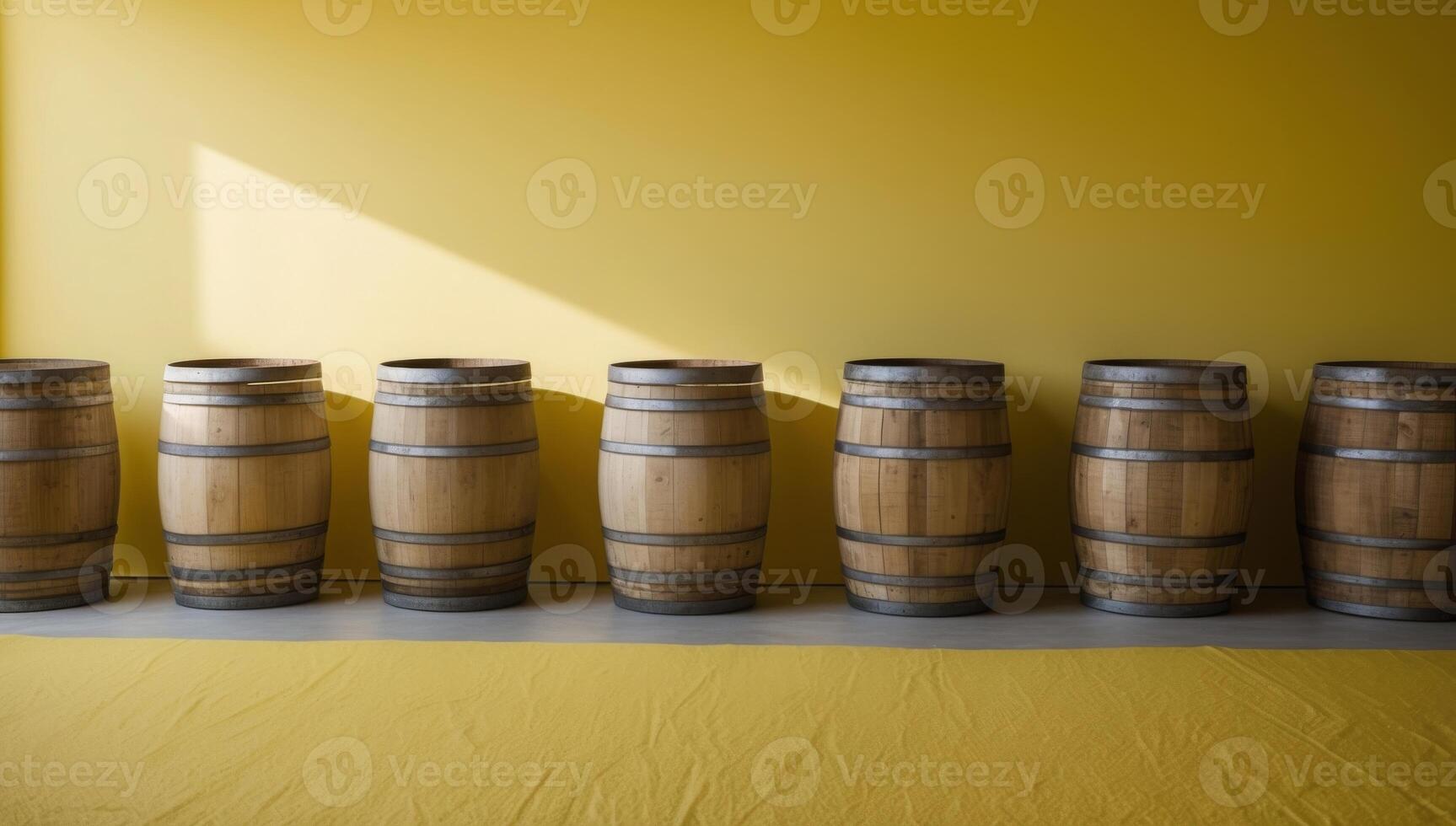 A row of weathered wooden barrels stands against a vibrant yellow background, showcasing rustic charm and a touch of rural authenticity. photo