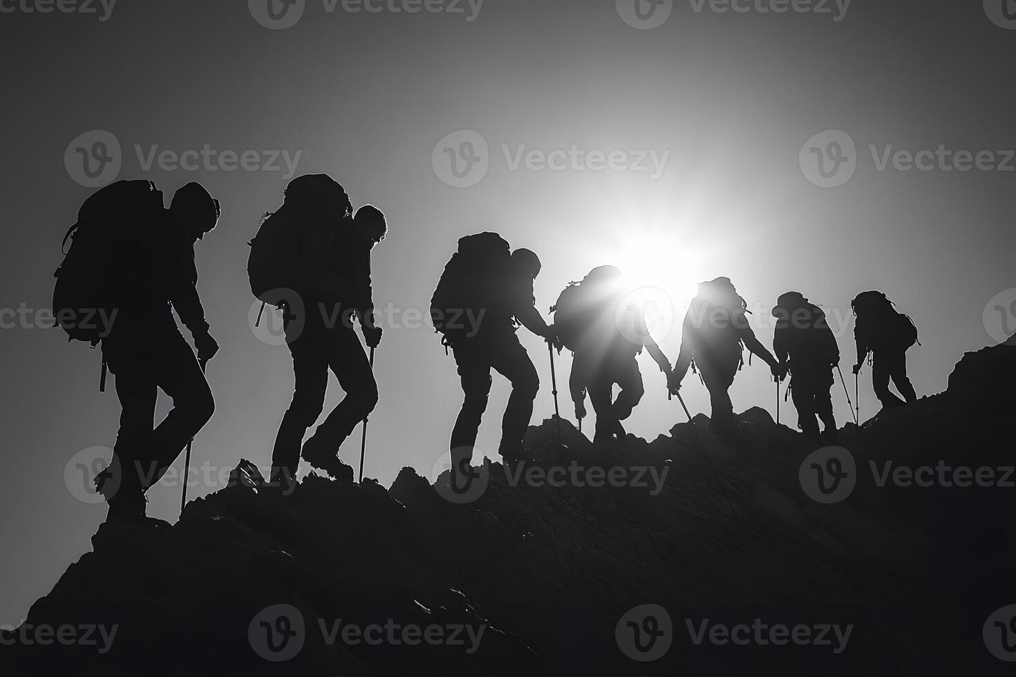 Silhouetted hikers ascend a challenging mountain peak photo