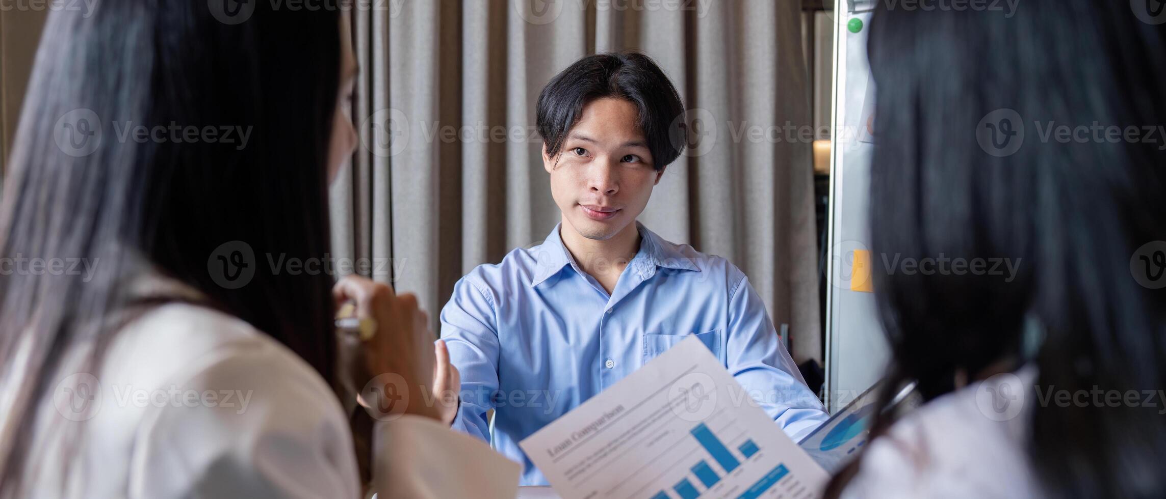 Male professional engaged in analytical discussion with diverse women during a business meeting photo