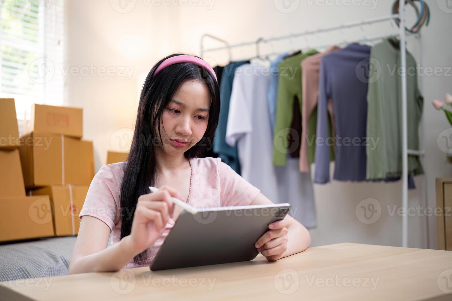 Young female entrepreneur managing her ecommerce clothing business using a tablet at home photo