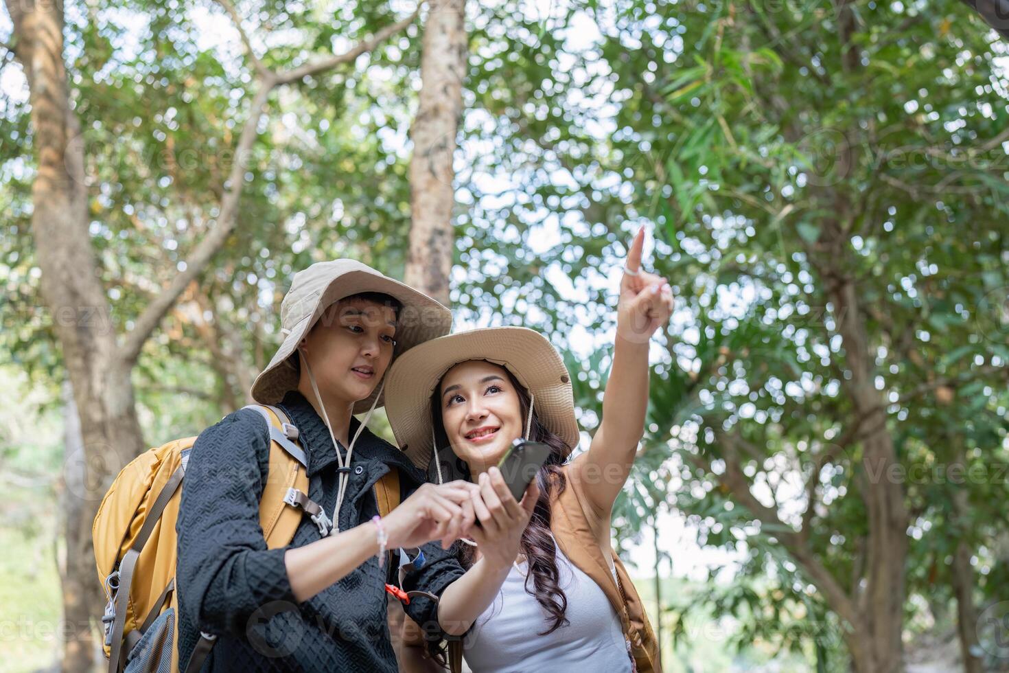 LGBT couple using a smartphone to navigate during their hiking adventure in nature photo