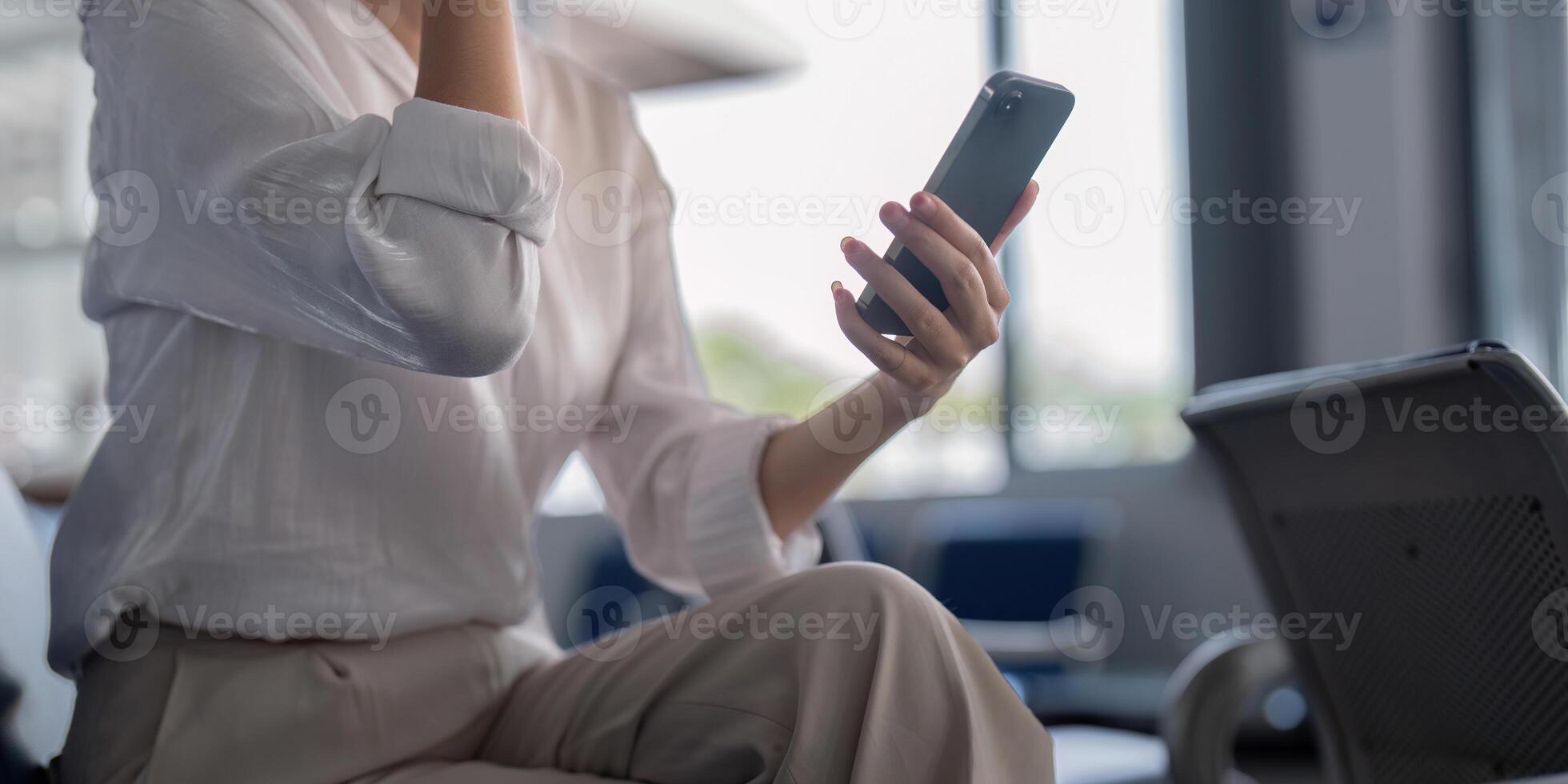 Close-up of young woman using smartphone while waiting in airport lounge, highlighting connection photo