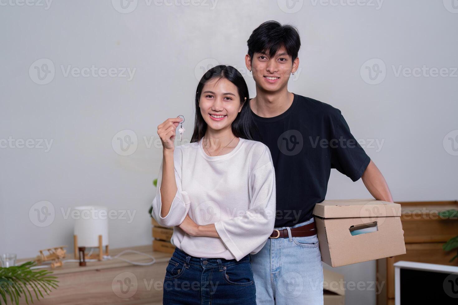 Joyful couple celebrating their new home with keys and moving boxes in a fresh space photo