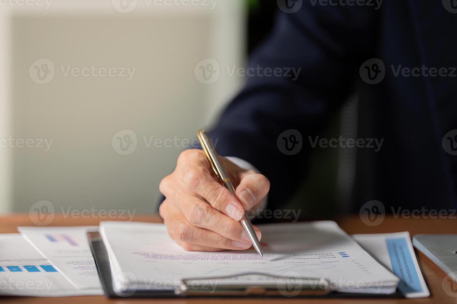 Senior accountant reviewing financial documents and writing notes on clipboard in modern office photo