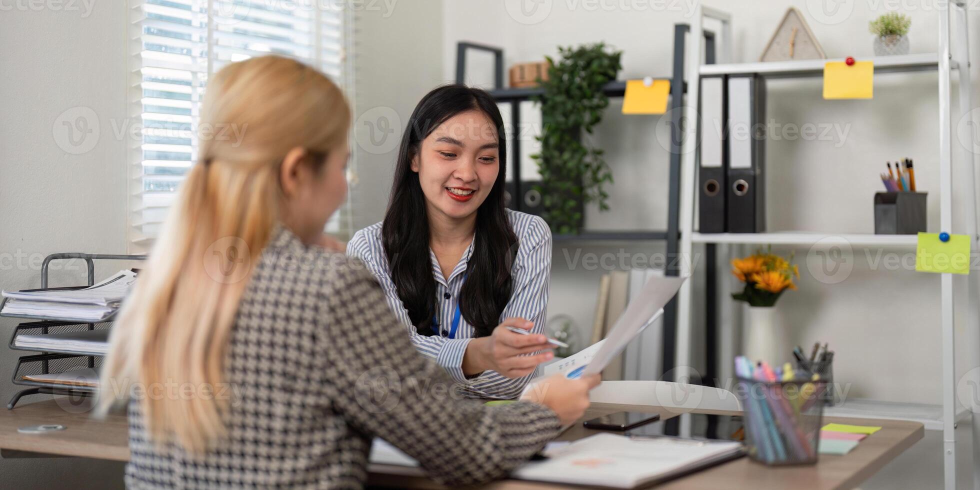 Businesswoman presenting project documents to a colleague in an inviting office setting filled with greenery photo