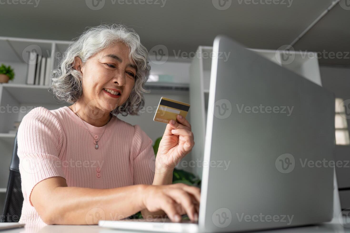 Senior woman shopping online using a credit card, enjoying a hassle-free experience at home photo