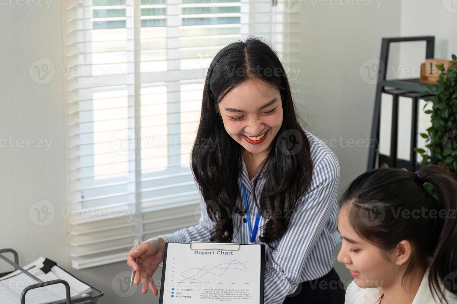 Businesswoman showcasing a report chart while discussing strategies with a colleague in a bright office photo