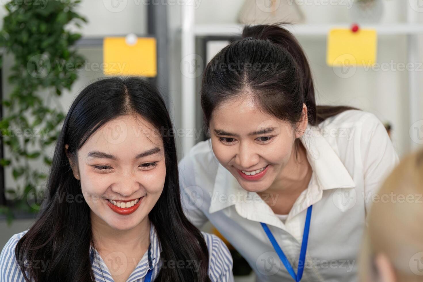 Two female professionals collaborating and laughing during a successful project discussion in a modern office photo