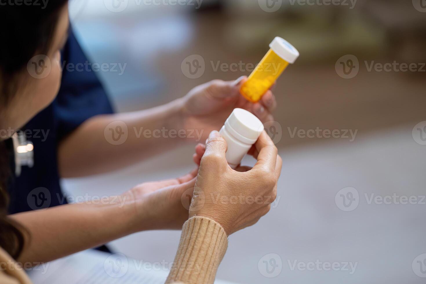 Elderly patient discussing symptoms with caregiver while holding medication bottles photo