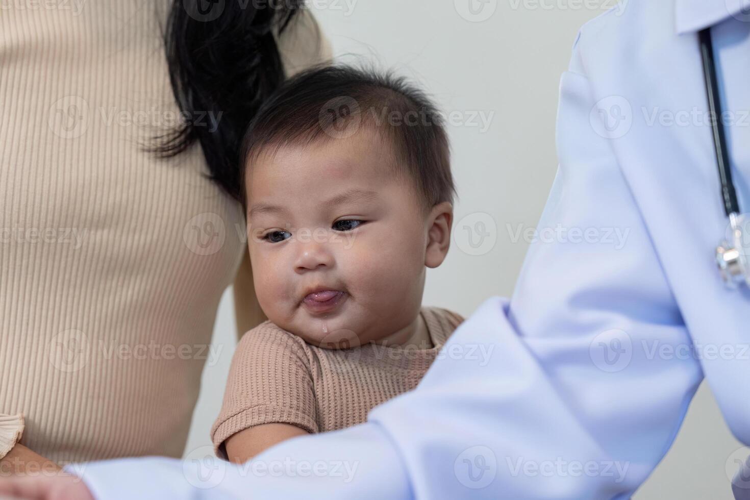 Pediatric doctor engaging with playful baby during a routine checkup with mother photo