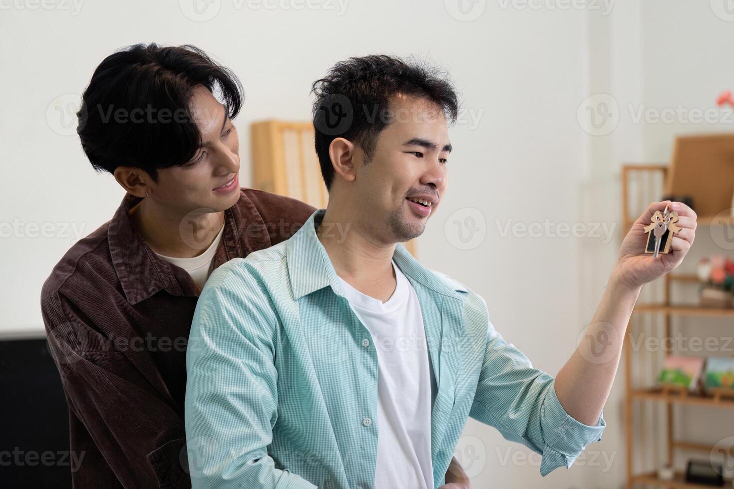 Gay couple celebrating their new home with house keys, embracing joyfully together photo