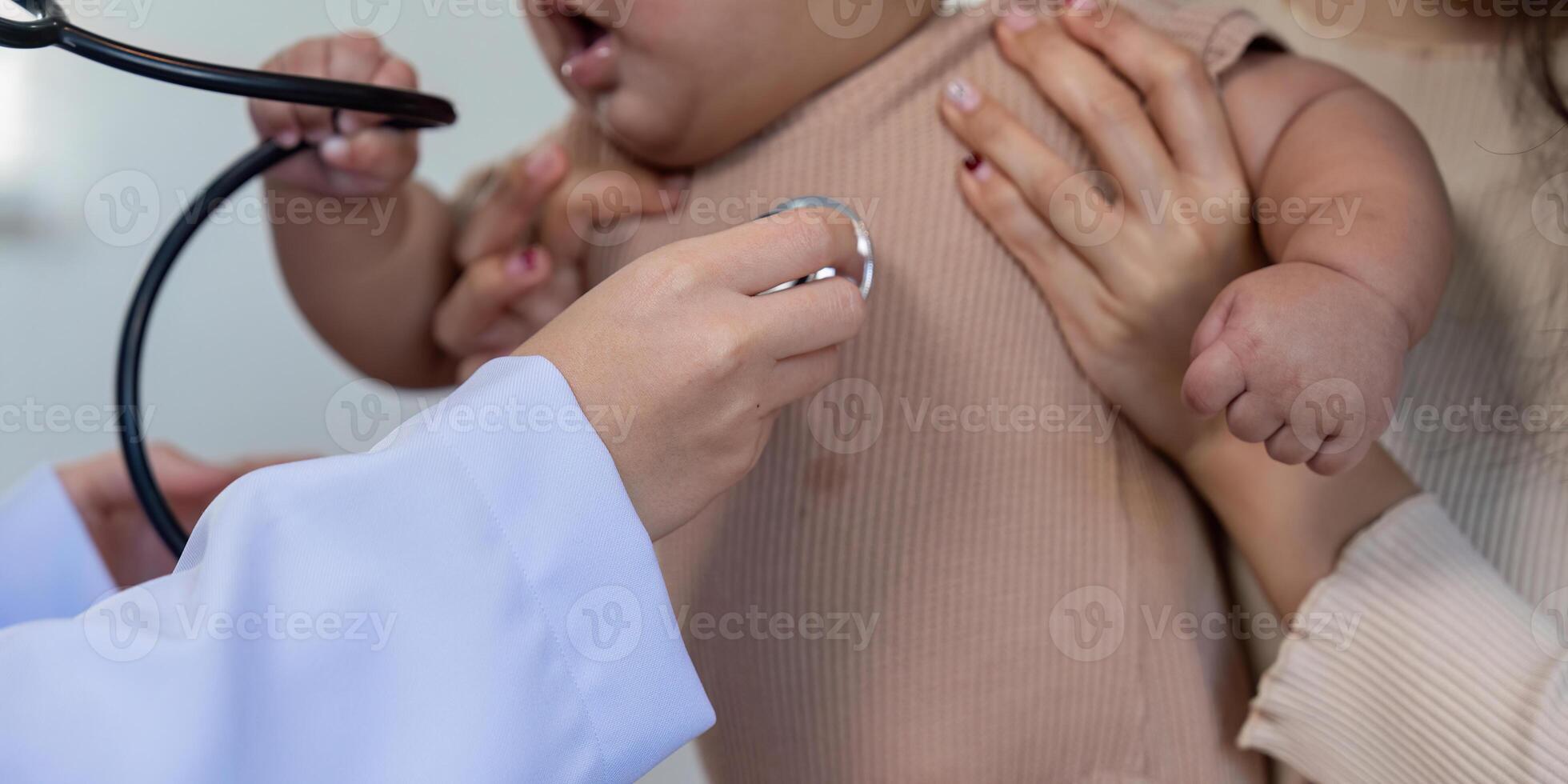 Doctor using stethoscope on baby during a pediatric checkup with parent support photo