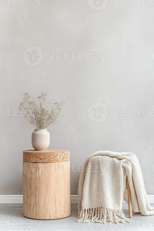 This setup presents a cork stool alongside a small bamboo table, adorned with a neutral throw blanket and a delicate potted plant, against a muted gray backdrop. Ample space invites creativity photo